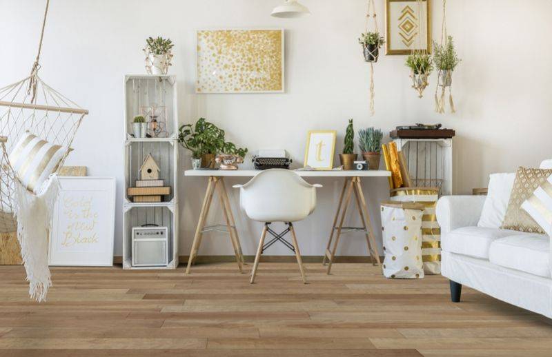 Bureau au décor blanc et doré avec plusieurs plantes et un plancher de bois verni